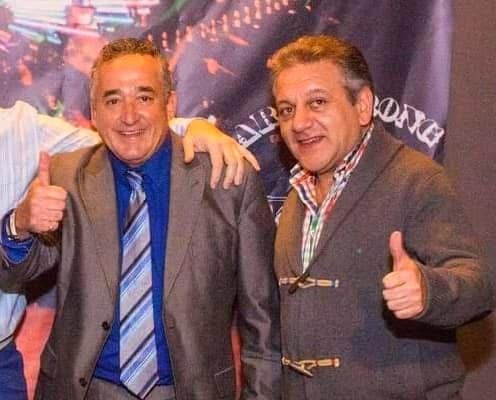 Dos hombres posando ante el cartel de Armstrong